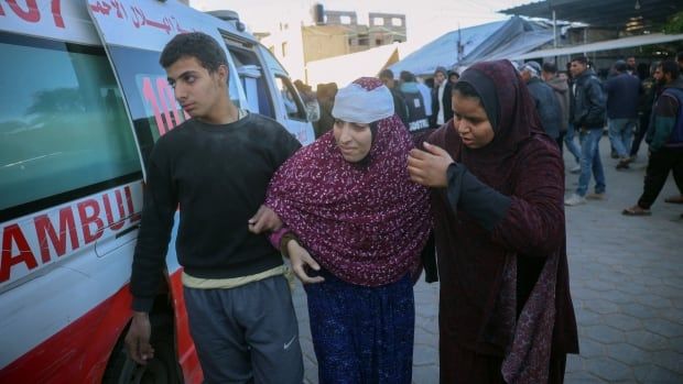 A woman is being helped out of an ambulance.