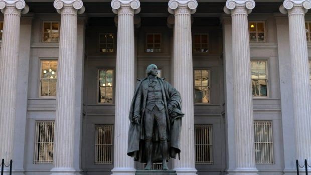 A green-coloured statue is seen in front of a large white government building.