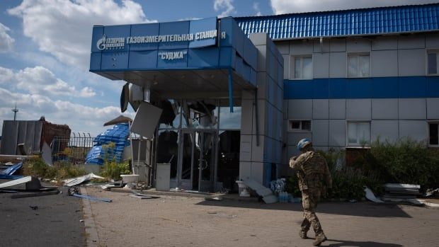 A soldier walks towards a blue and white building. 