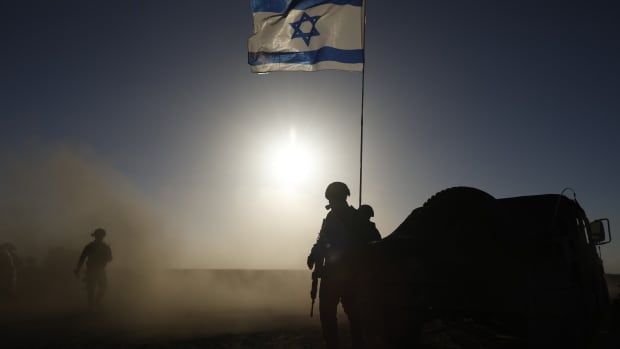 Soldiers with the Israel Defense Forces stand near a military vehicle.