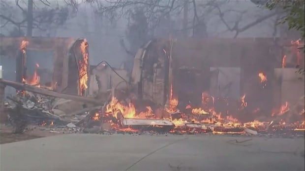 Furniture and walls of what remains of a house are on fire.