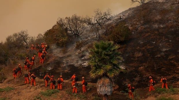 People in orange jump suits  in  a  hazy smoky hill