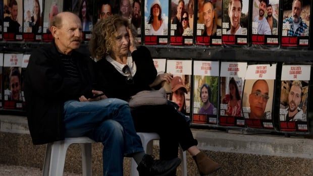 A couple sits beside a display of posters. 