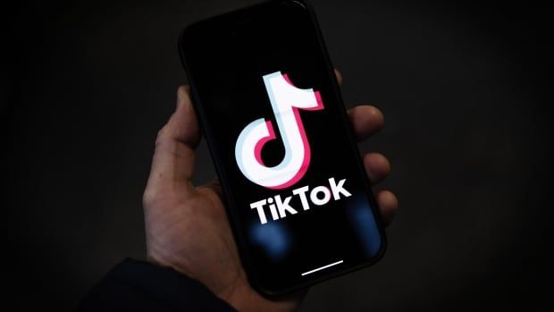 A hand holding a phone with TikTok on the screen.