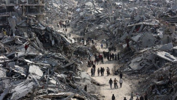 People walk on a pathway through the rubble of northern Gaza. 