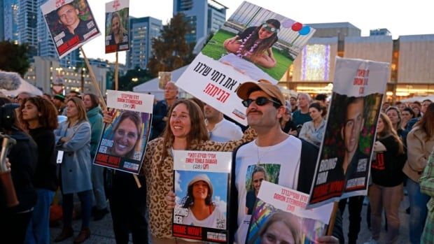 People hold posters of Israeli hostages. 