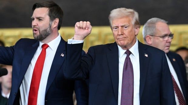 Donald Trump raises his fist, standing next to vice president J.D. Vance.