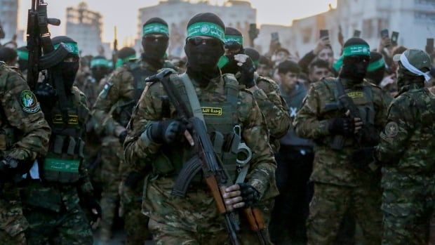 Hamas fighters escort a Red Cross vehicle to collect Israeli hostages released after a ceasefire agreement between Israel and Hamas took effect, in Gaza City Sunday, Jan. 19, 2025. 