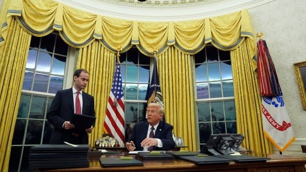 A man sits at a desk signing documents.