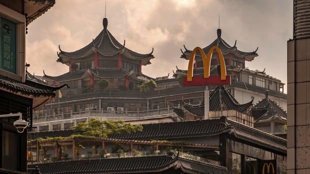 The golden arches of McDonald's appear over a building with a curved roof in the style of classical Chinese architecture. Other buildings with similar aesthetics are seen in the horizon. 