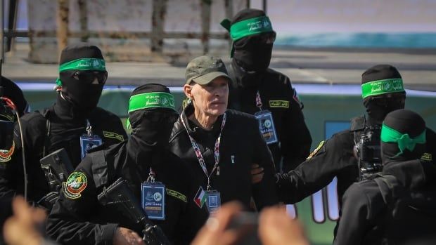 A man wearing a baseball hat is surrounded by masked men.