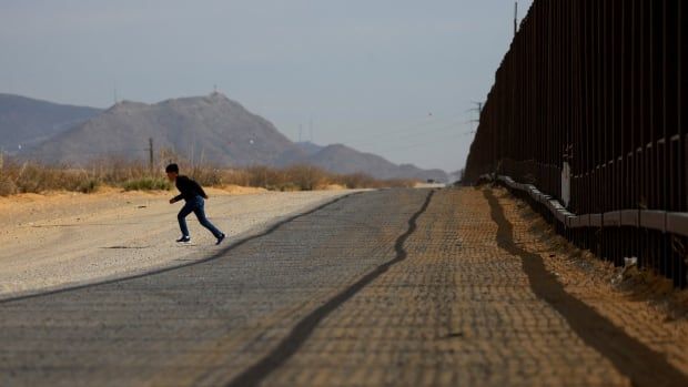 A man runs at the wall separating the United States and Mexico