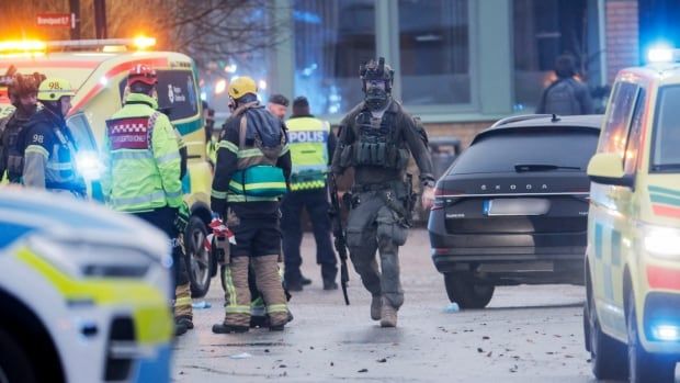 Armed police, firefighters and paramedics gather at a crime scene.