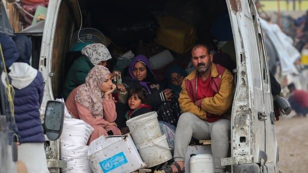 A family sits in the back of a loaded van.