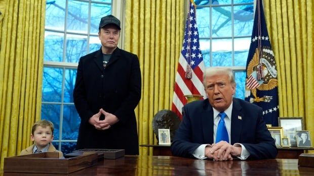 Two men in suits, one with a T-shirt underneath and one with a shirt and tie, are seen in the Oval Office with American flags. A child is also present.