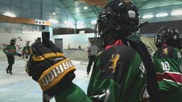 hockey player looking onto players on the ice rink