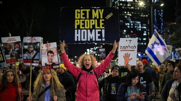 Demonstrators hold signs and pictures of hostages.