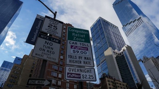 Congestion Relief Zone signage stands is seen against the New York City skyline on a sunny day.