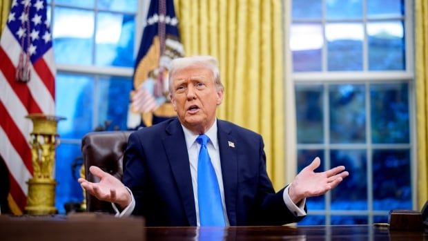 U.S. President Donald Trump gestures while sitting at his desk in the Oval Office.