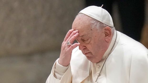 A person in religious garb touches their forehead with their fingers.