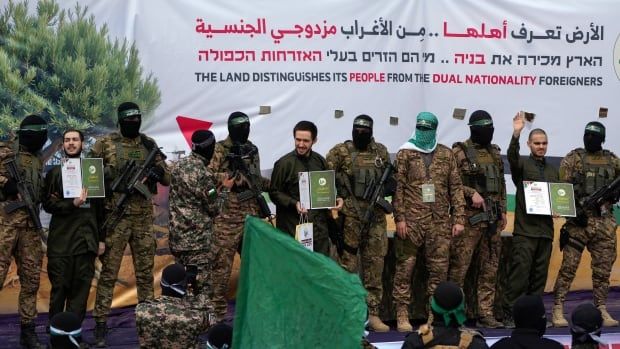 People holding up booklets are seen on stage surrounded by armed guards.