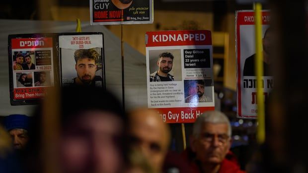 People hold signs showing photos of a man with words including 'Kidnapped' and 'Bring Them Home.'