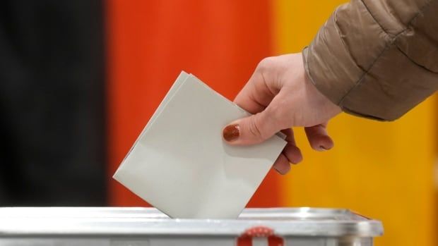 A person casts a ballot into a box.