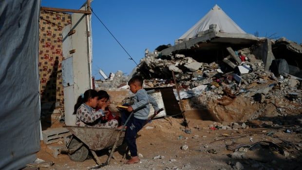 Children play with a wagon near rubble.