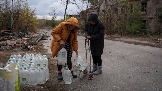 People in Chasiv Yar, Ukraine, put bottles of water on a cart.