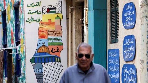 A man walks in front of a mural.