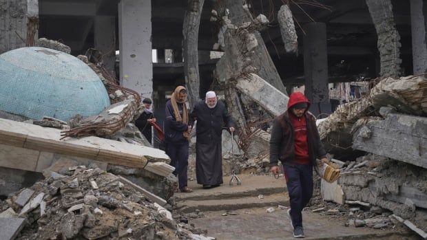 People walk through rubble.