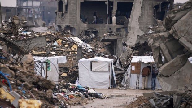 Tents sit next to the rubble of destroyed buildings.