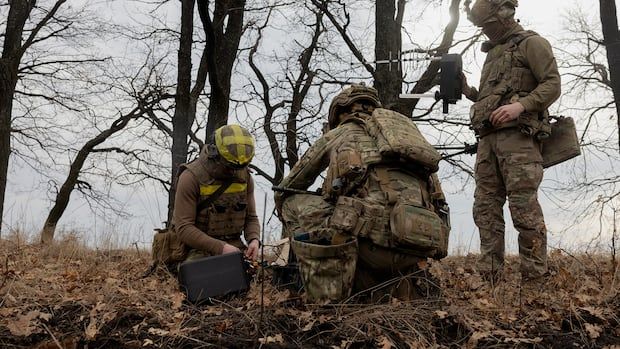 Three men in military fatigues using equipment.