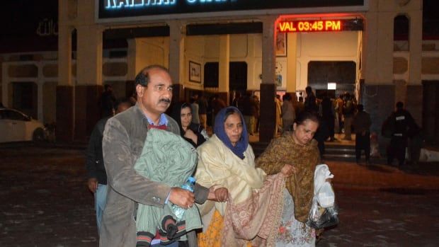 People hold their belongings outside a train station.