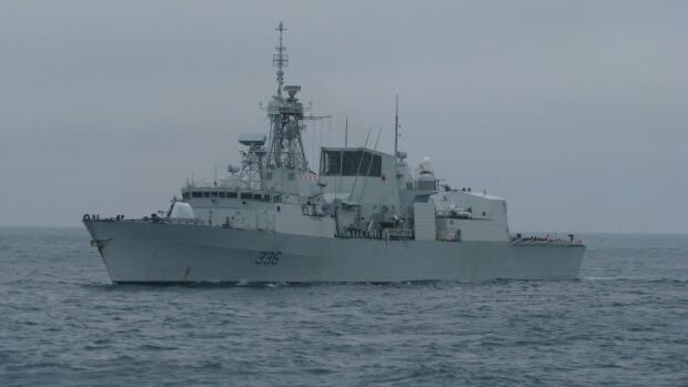 A large grey Canadian warship floats alone in open water, with no land in sight.