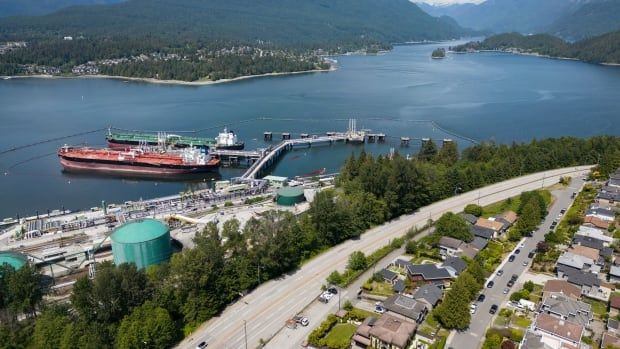 An aerial view of crude oil tankers at a dock in summer amid mountains of B.C.