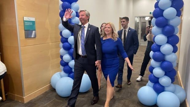 A family walks down a hallway flanked by blue balloons.