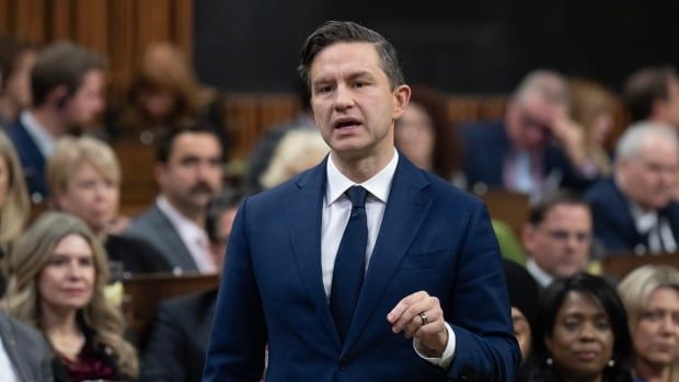 A man in a blue suit gestures with his hand as he speaks in the House of Commons.