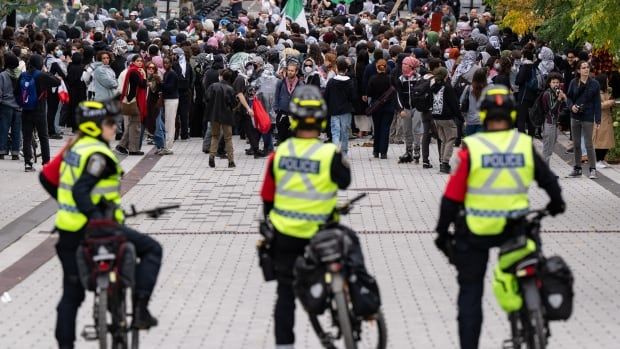 Police watch as attendees march near McGill University campus during a pro-Palestinian demonstration on the anniversary of a Hamas attack on Israel that triggered the ongoing war in Gaza, in Montreal, Monday, Oct. 7, 2024.