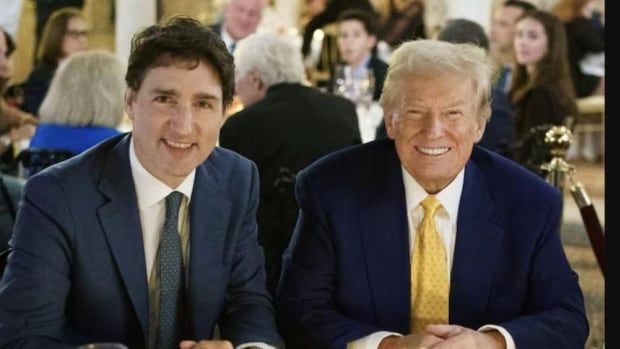 Two men sit at a dinner table and smile.