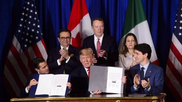 Group of people signing documents with flags in back