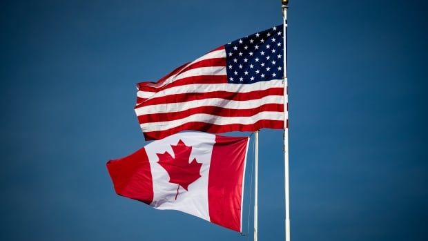 canada and U.S. flags blowing in the wind