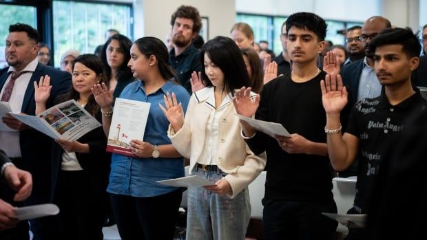 Several people stand and hold their right hands up as they take an oath.