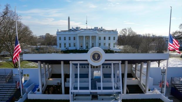 The White House is shown, behind a temporary edifice that is covered with stands for seating.