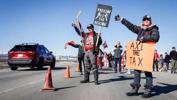 Anti-carbon tax protesters wave signs and chant slogans as they block a westbound lane of the Trans Canada highway near Cochrane, Alta., in April.