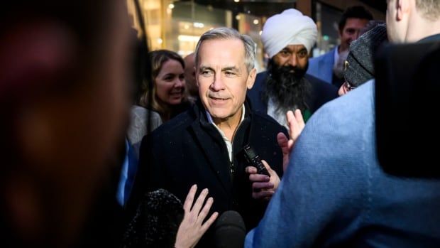 Mark Carney surrounded by microphones in Ottawa.