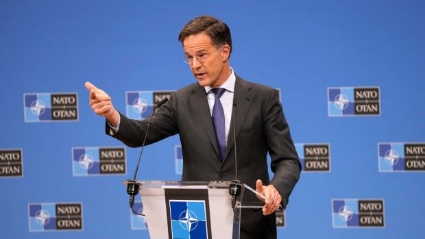 A person gestures while speaking at a lectern.