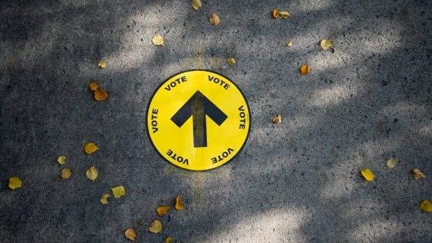 A large yellow sticker on the ground that says “vote” with an arrow pointing up.