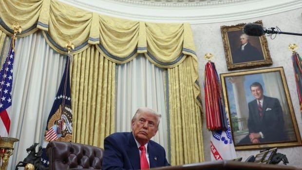 A man sits at a desk in the Oval Office