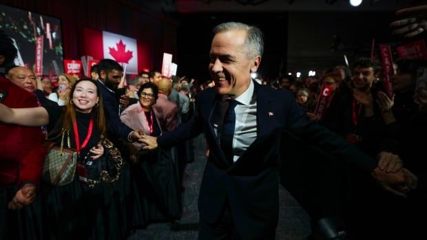 A person in a suit greets supporters.